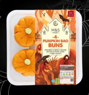 A packet of M&S pumpkin bao buns in front of a black halloween background with cobwebs