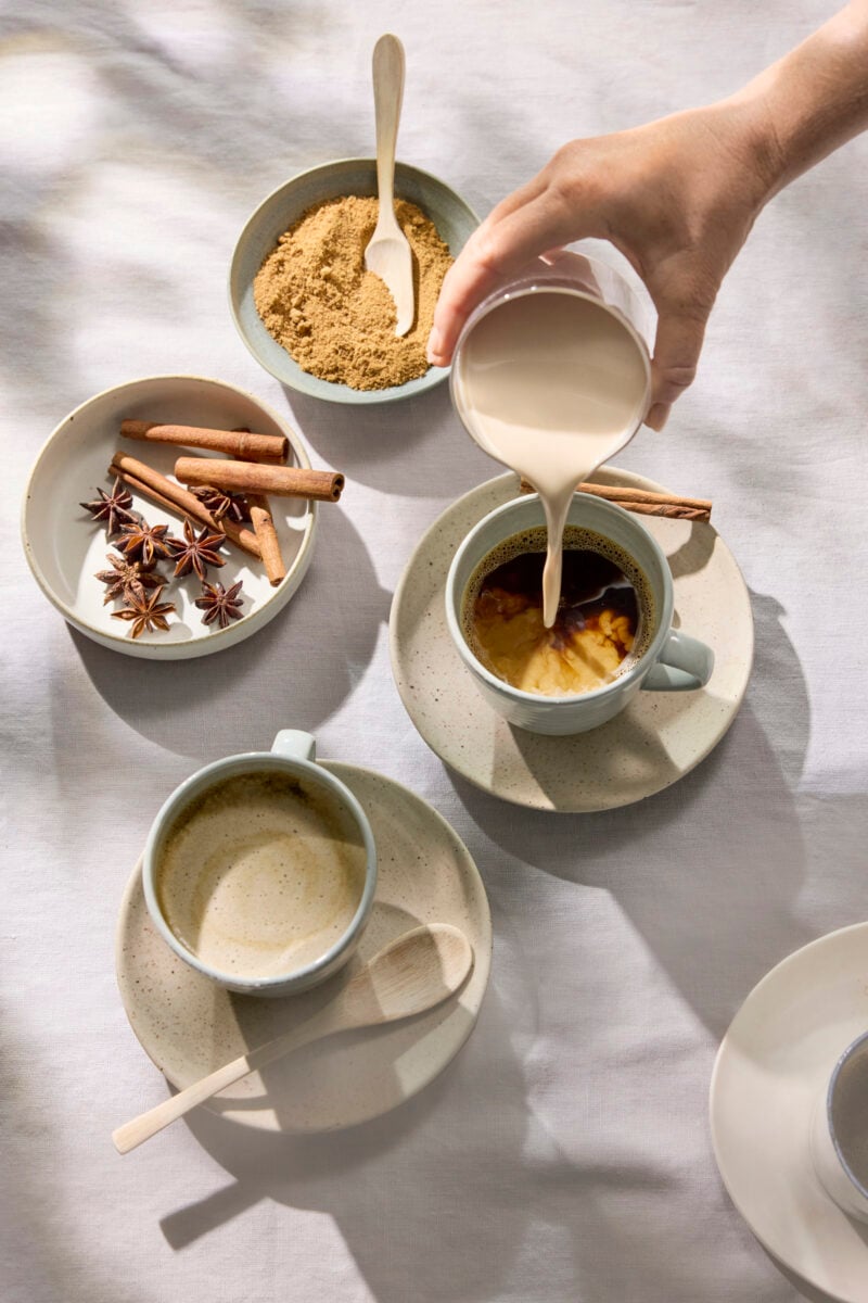 A person pouring plant-based milk into coffee