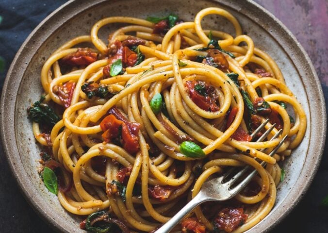 vegan bucatini pasta with sun-dried tomato, tomato, balsamic vinegar, garlic, onion, and baby spinach, vegan Italian recipes