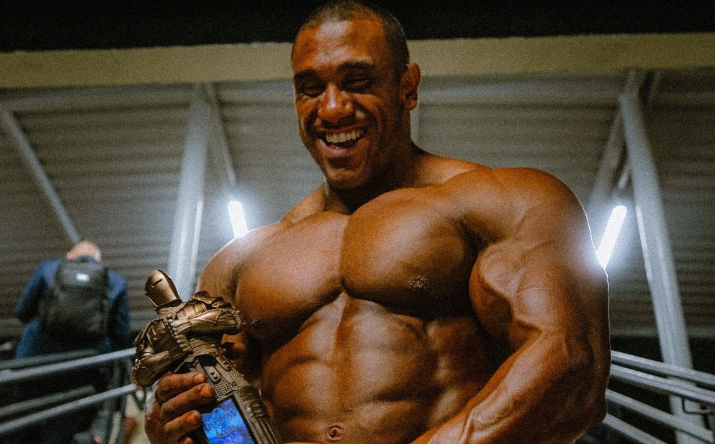 Photo shows Guilherme Oliveira holding his bodybuilding trophy for winning Mr Olympia Brazil