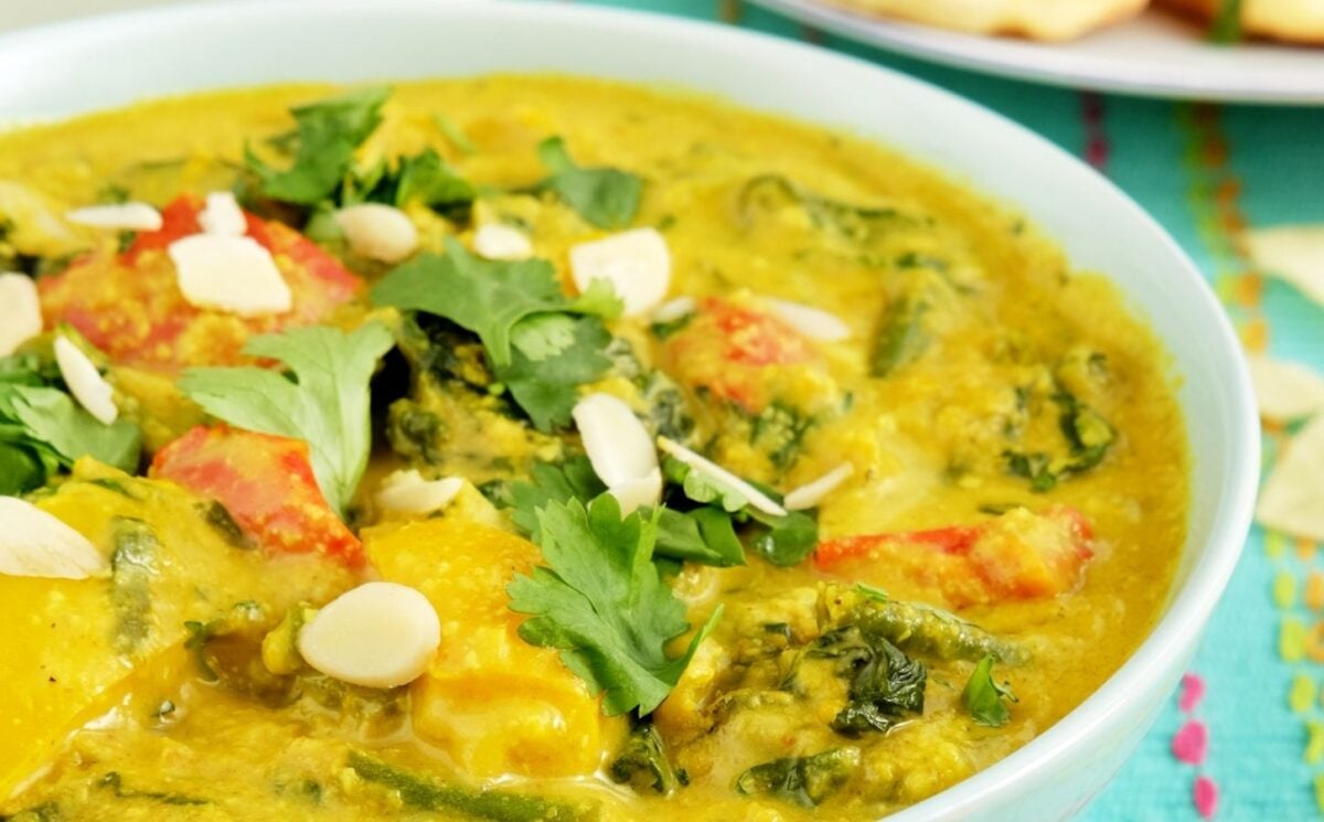 a picture of a vegan vegetable korma made with green beans, spinach, turmeric, and coconut milk