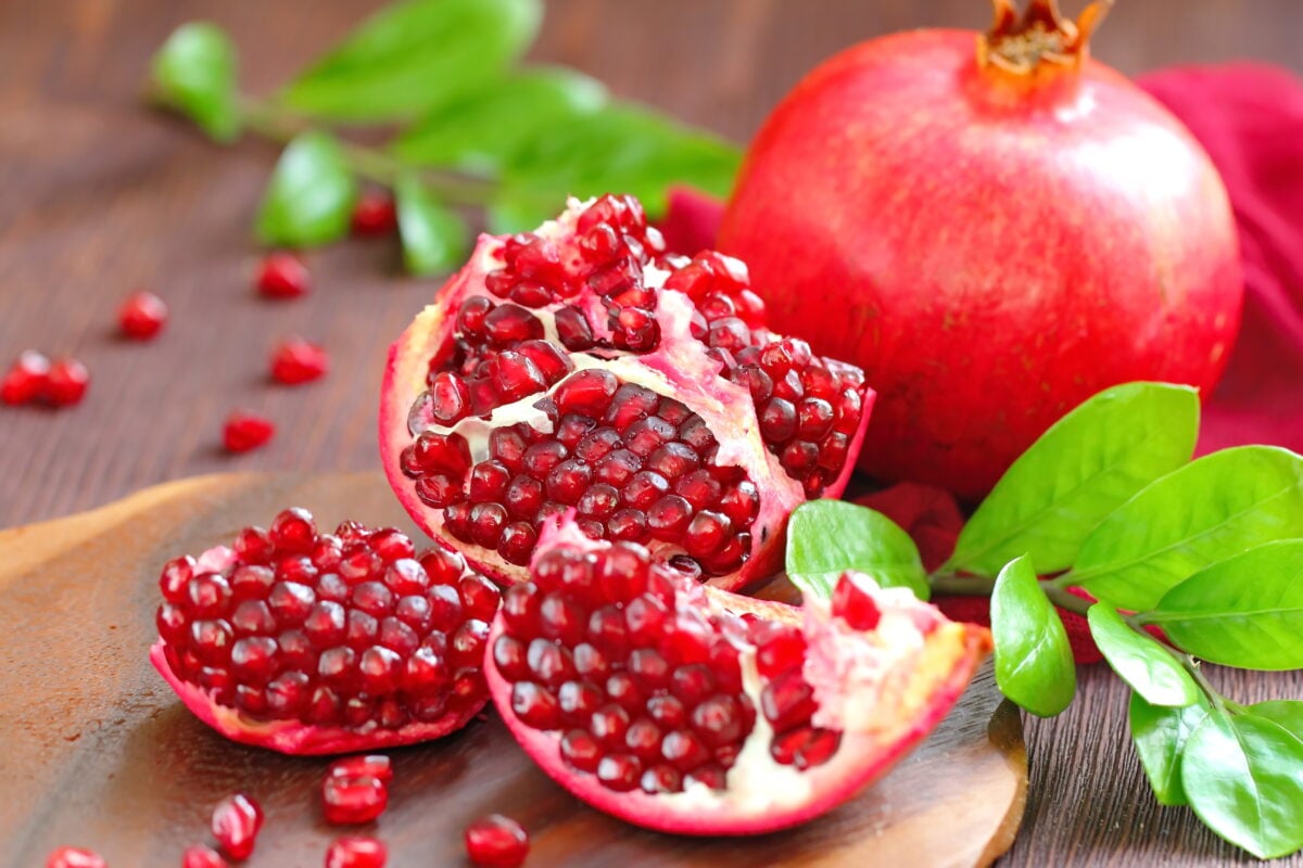 Photo shows one whole and one halved pomegranate