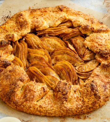 an image of an almond pear galette with slices of almond and pear surrounding the tart