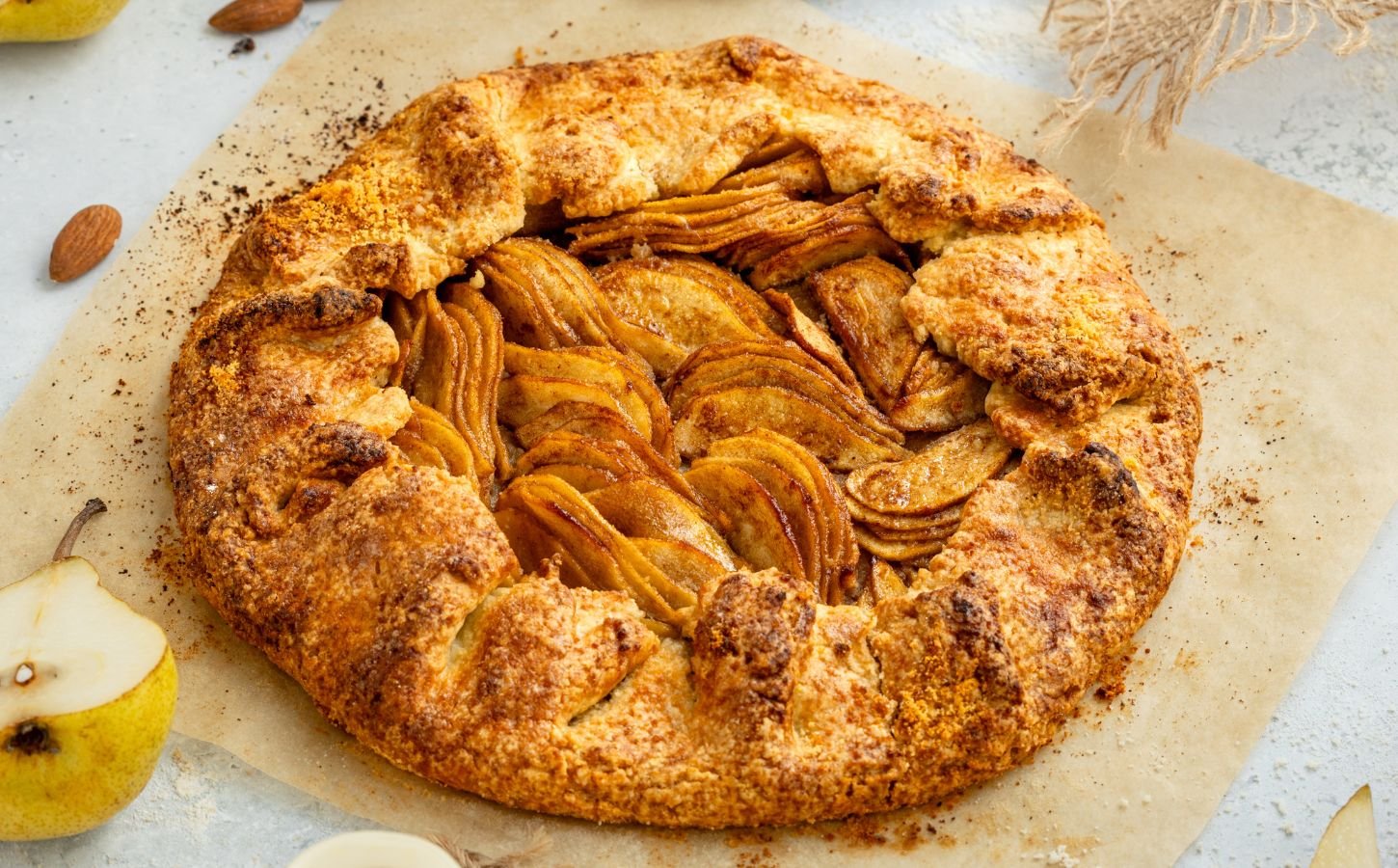 an image of an almond pear galette with slices of almond and pear surrounding the tart