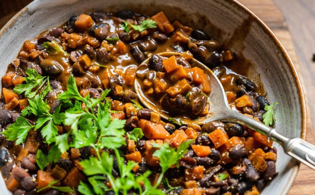 A bowl of vegan black bean goulash featuring lots of carrots and herbs