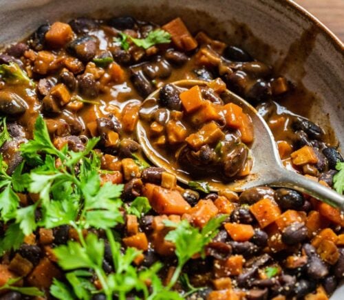 A bowl of vegan black bean goulash featuring lots of carrots and herbs