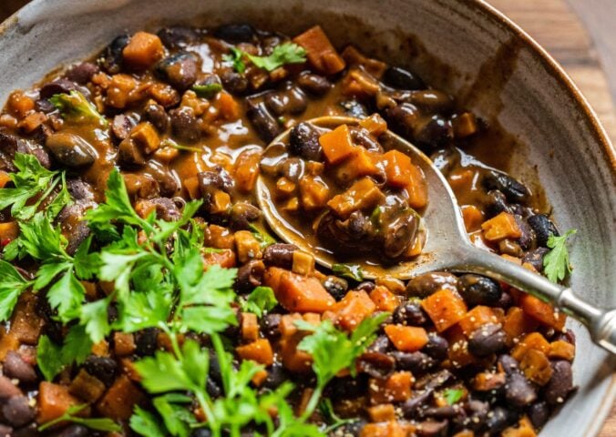 A bowl of vegan black bean goulash featuring lots of carrots and herbs