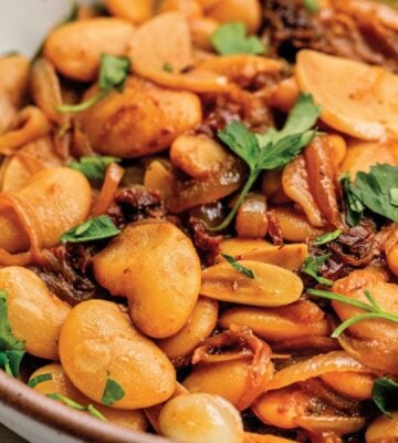 a bowl of caramelized onion butter beans made with sun-dried tomatoes and jammy onions