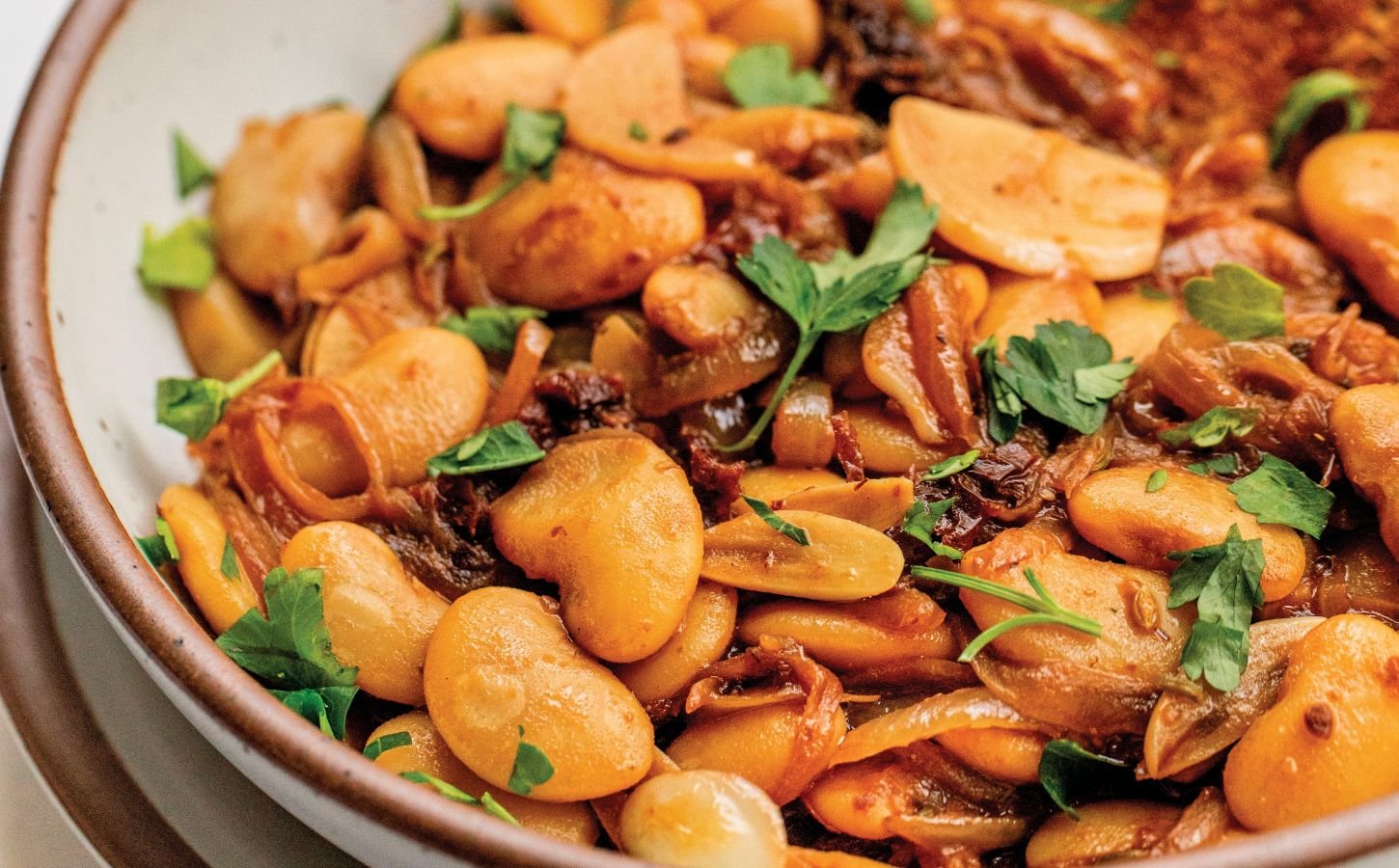 a bowl of caramelized onion butter beans made with sun-dried tomatoes and jammy onions