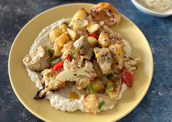 A yellow plate full of vegan cauliflower and potato bake