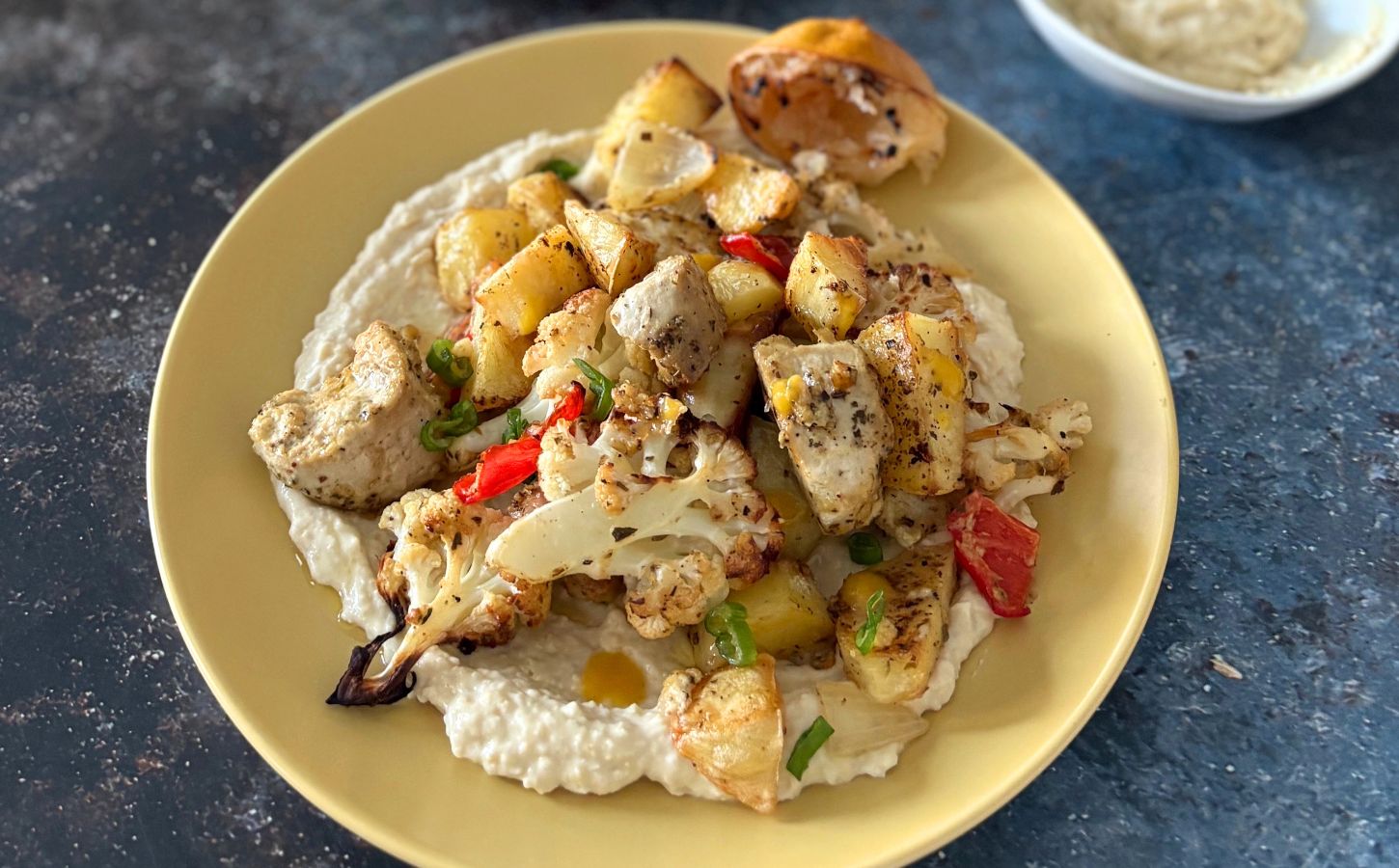 A yellow plate full of vegan cauliflower and potato bake