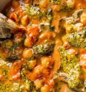 A creamy vegan pesto chickpea bowl with some crusty bread dipped in it