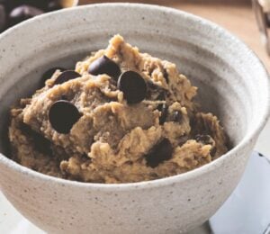 a bowl of chickpea cookie dough with dark chocolate chips, protein powder, and peanut butter