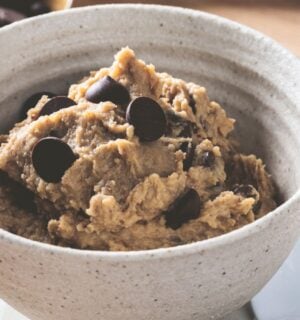 a bowl of chickpea cookie dough with dark chocolate chips, protein powder, and peanut butter