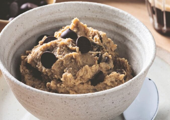 a bowl of chickpea cookie dough with dark chocolate chips, protein powder, and peanut butter