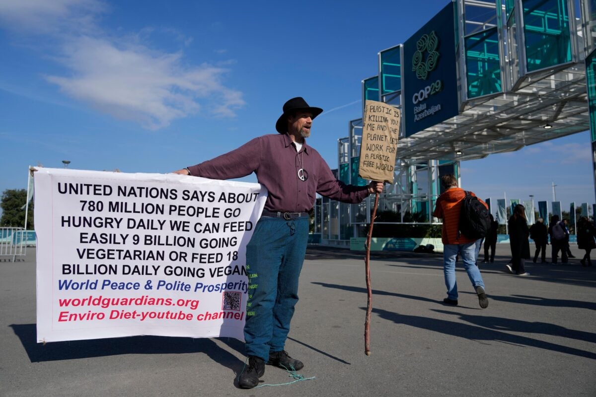 A man holding a sign calling for a plant-based food system outside COP29