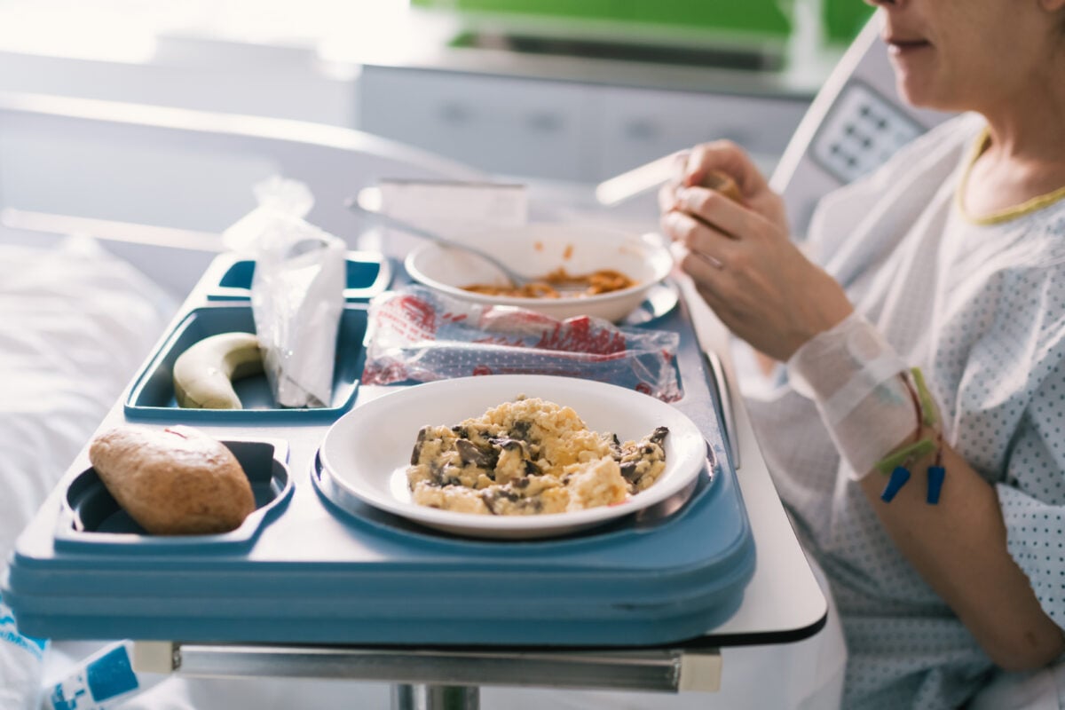 A woman eating hospital food in a hospital bed