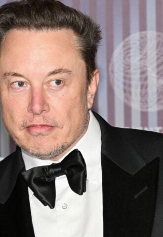 Elon Musk wearing a suit on a red carpet