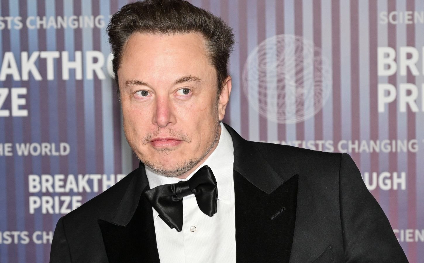 Elon Musk wearing a suit on a red carpet