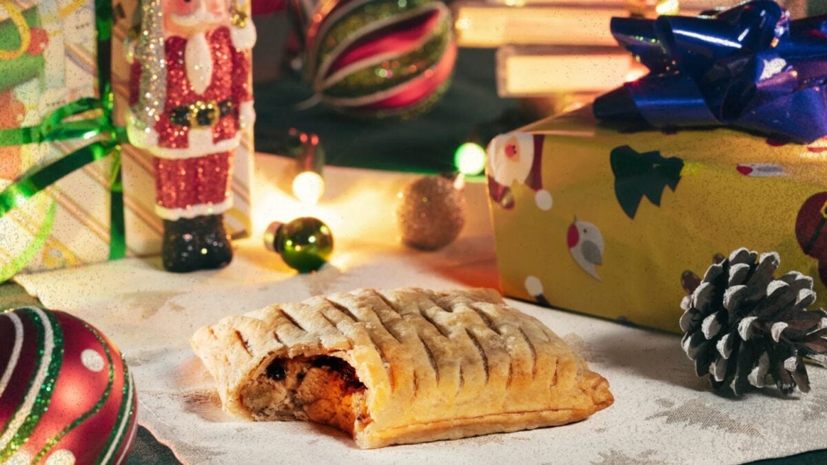 Photo shows the Greggs Vegan Festive Bake on a table with wrapped presents and other festive accoutrements