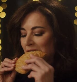 Photo shows Nigella Lawson taking a bite of a Greggs Festive Bake, which is also available as a vegan menu item