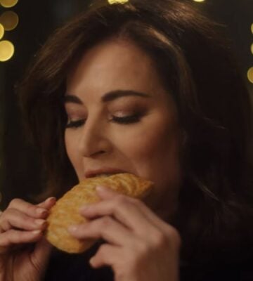 Photo shows Nigella Lawson taking a bite of a Greggs Festive Bake, which is also available as a vegan menu item