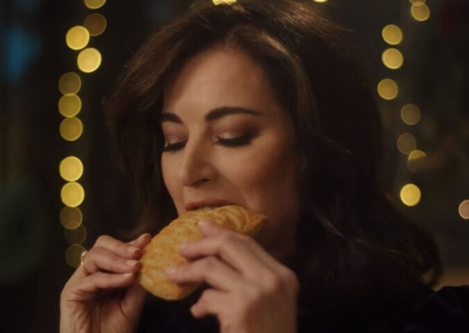 Photo shows Nigella Lawson taking a bite of a Greggs Festive Bake, which is also available as a vegan menu item