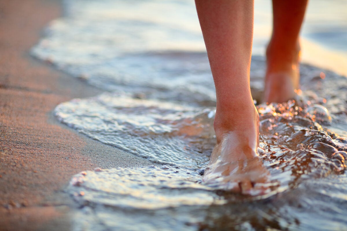 A person walking barefoot on the beach