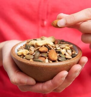 Photo shows someone eating nutritious nuts and seeds out of a wooden bowl