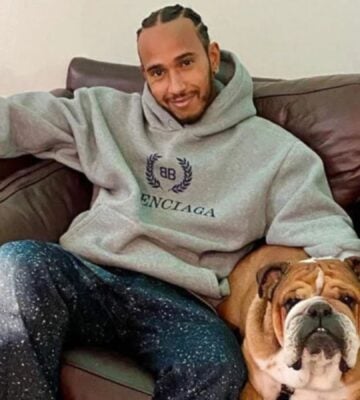 Vegan celebrity Lewis Hamilton sitting with his plant-based dog Roscoe on a sofa