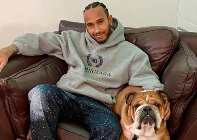 Vegan celebrity Lewis Hamilton sitting with his plant-based dog Roscoe on a sofa