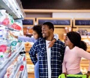 Photo shows a young family shopping in the refrigerated section of a supermarket