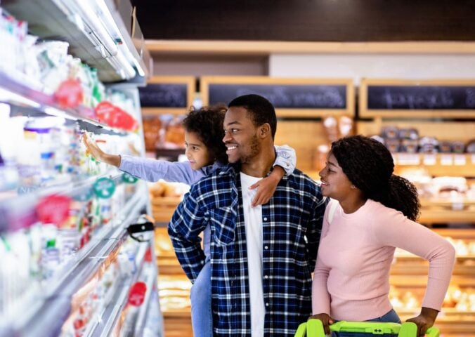 Photo shows a young family shopping in the refrigerated section of a supermarket