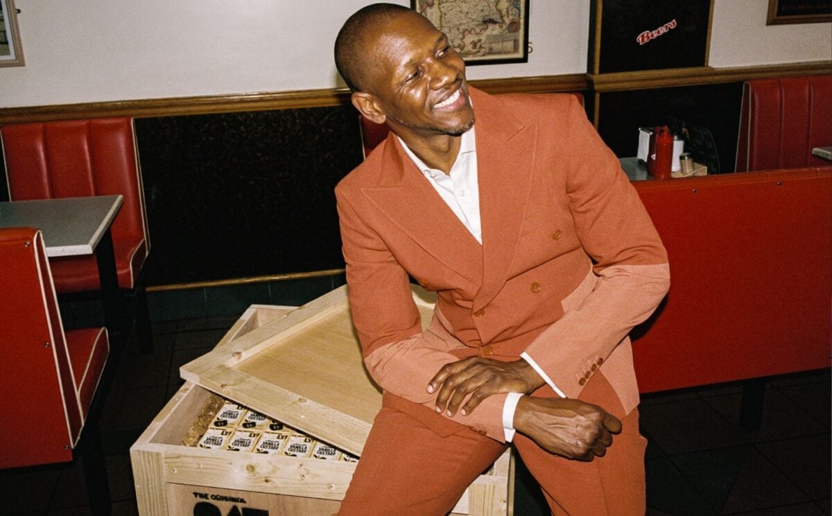 A photo of British rapper Giggs sitting on a crate of Oatly cartons