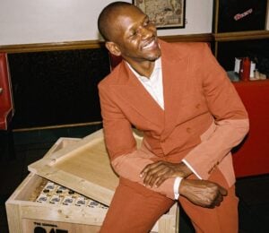 A photo of British rapper Giggs sitting on a crate of Oatly cartons