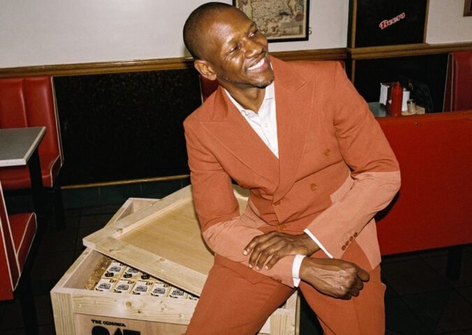 A photo of British rapper Giggs sitting on a crate of Oatly cartons