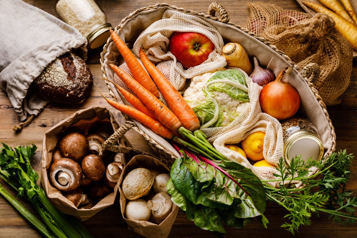 Photo shows a selection of plant-based whole foods like mushrooms, carrots, apples, and lemons