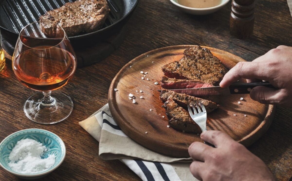 Photo shows someone's hands as they cut into a large beef steak