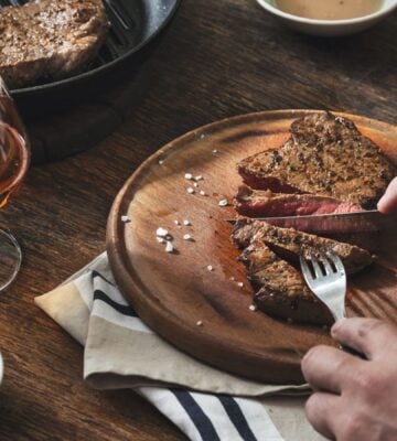 Photo shows someone's hands as they cut into a large beef steak