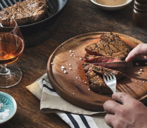 Photo shows someone's hands as they cut into a large beef steak