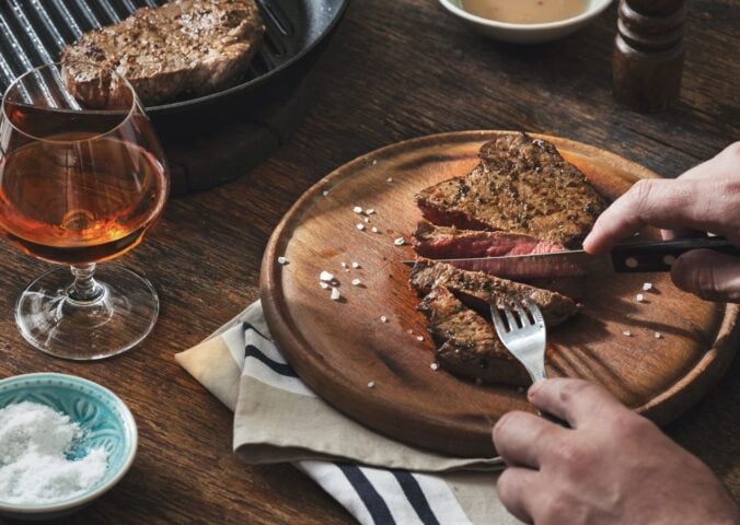 Photo shows someone's hands as they cut into a large beef steak