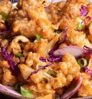 a plate of fried sweet and sour cauliflower with garnish