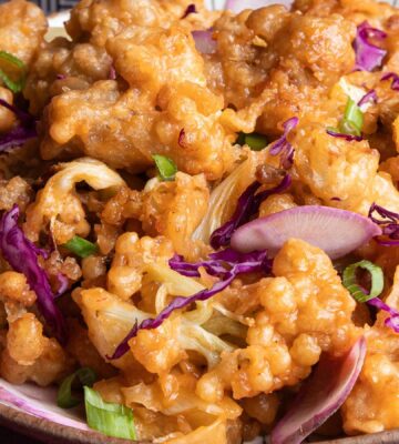 a plate of fried sweet and sour cauliflower with garnish