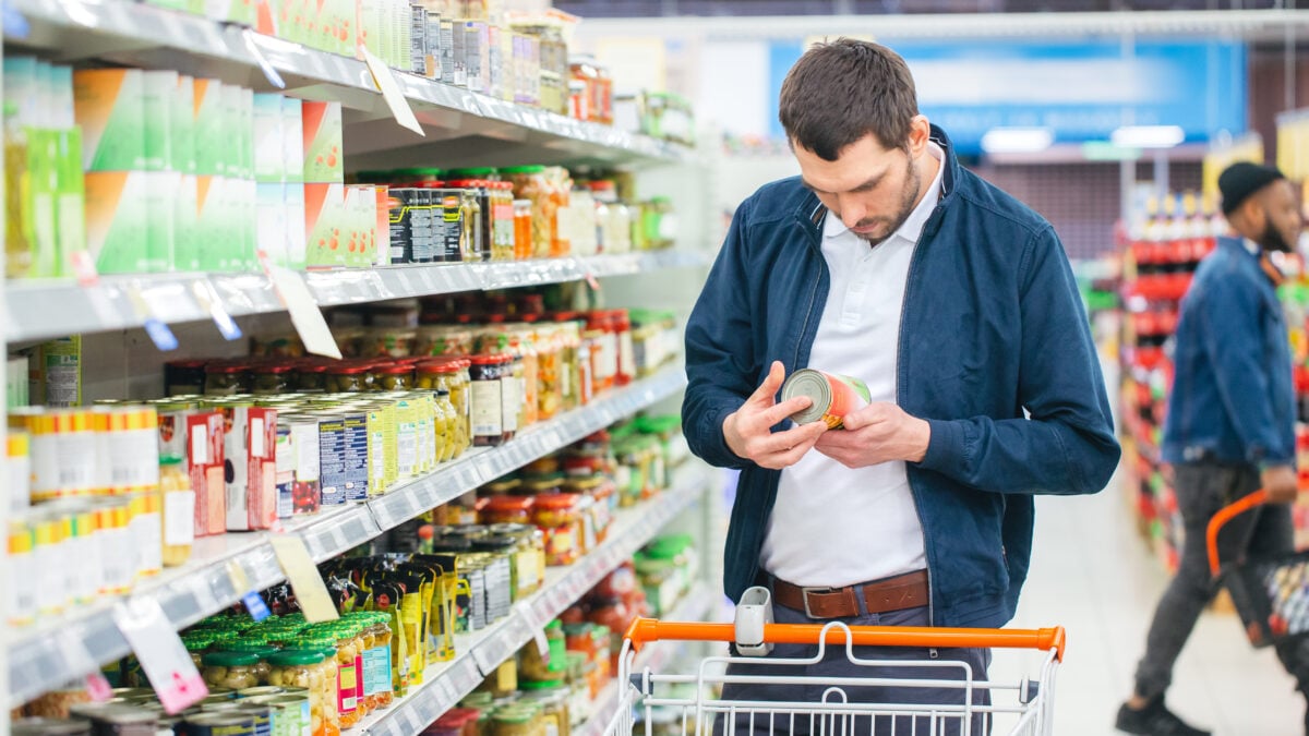 A man looking at a label on a can of food