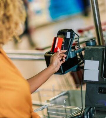 Photo shows a woman paying for food shopping with a credit card