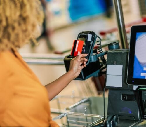 Photo shows a woman paying for food shopping with a credit card