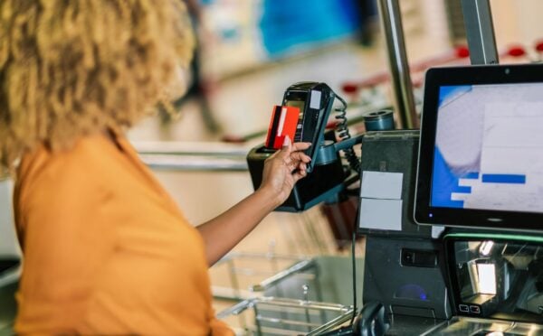 Photo shows a woman paying for food shopping with a credit card