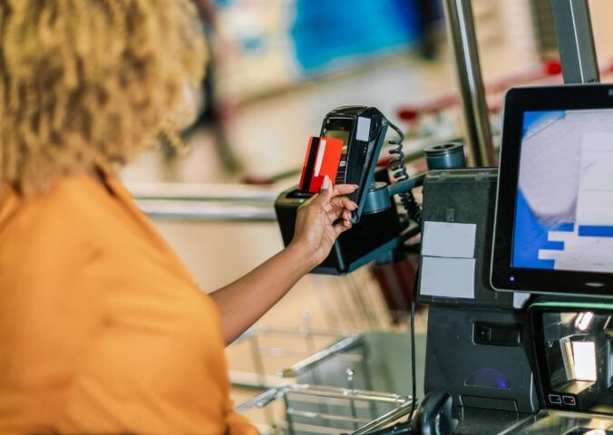 Photo shows a woman paying for food shopping with a credit card