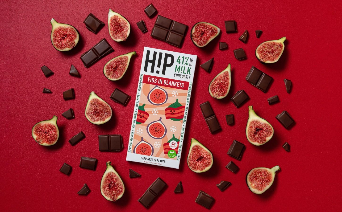 Photo shows the new H!P fig and vegan bacon chocolate bar on a red background, surrounding by pieces of chocolate, figs, and bacon