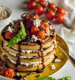 a stack of savory and vegan almond ricotta pancakes topped with cherry tomatoes and balsamic glaze